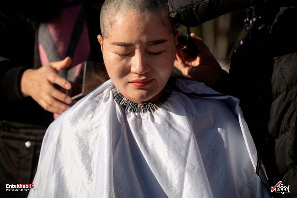 عکس: یک زن در چین در اعتراض به بازداشت شوهرش سر خود را تراشید